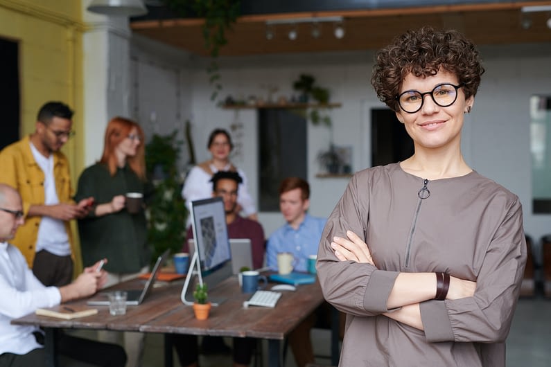 woman leader in room with team working at desk behind her