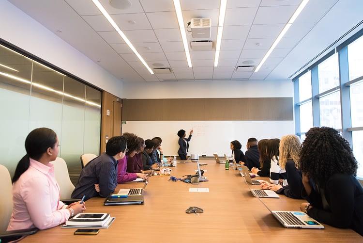 leader at whiteboard with her team in conference room