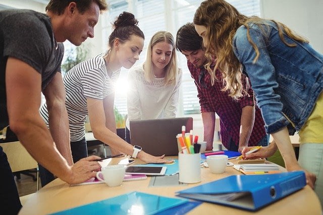 team standing and working together over laptop