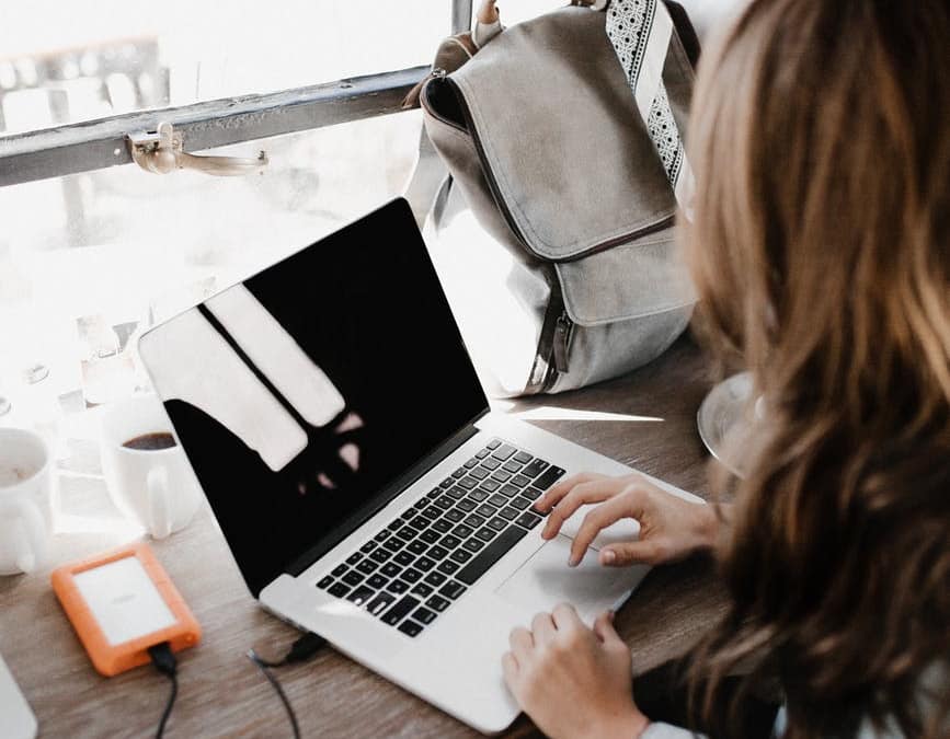 close up photography of woman sitting beside table while using macbook