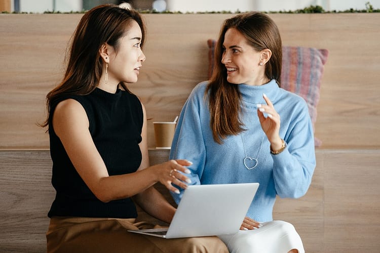 two female entreprenur partners casually dressed and looking at computer together